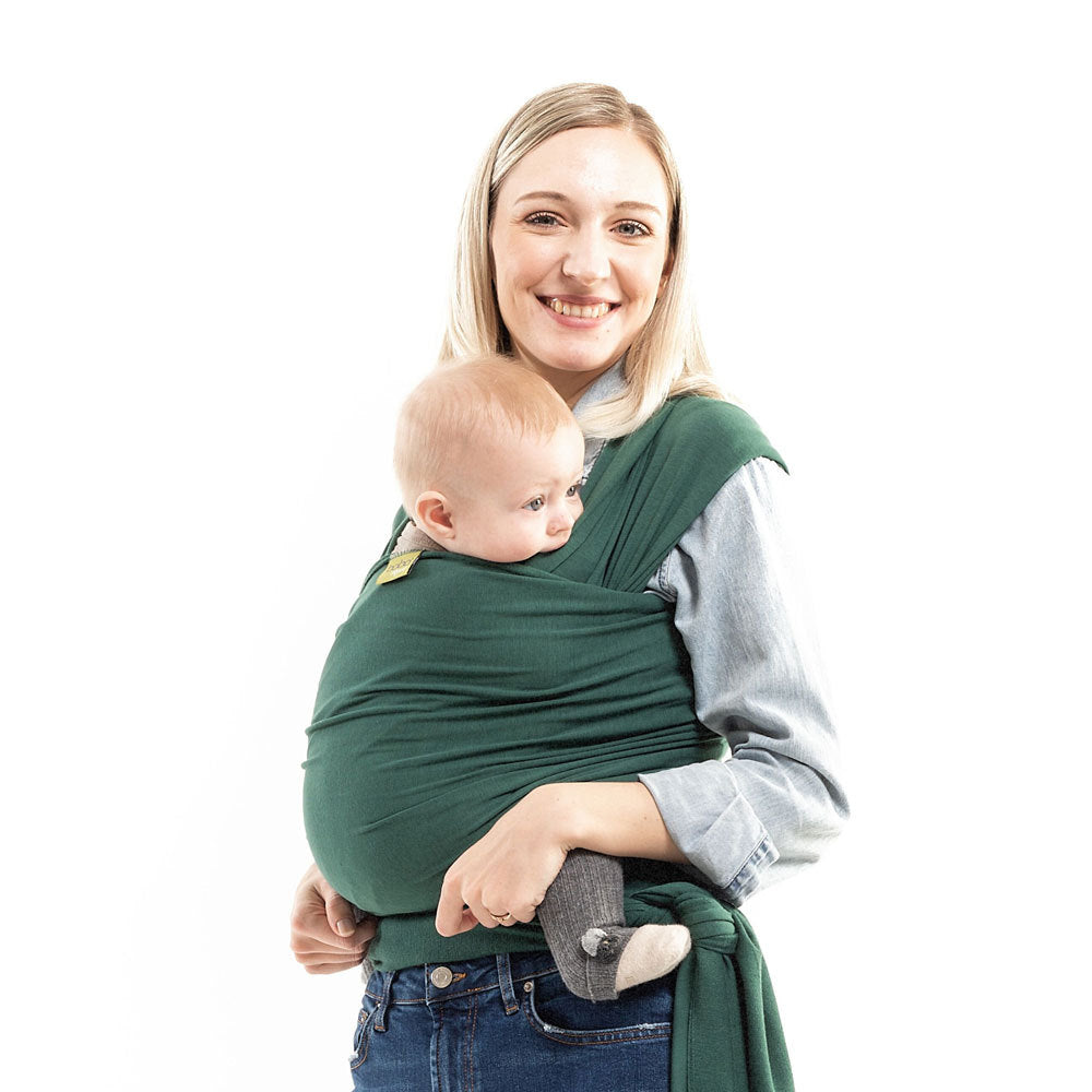 Woman holding a baby in a green sling against a white background