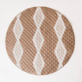 A brown circle quilted playmat with a maori insrpired design on a natural colour background. 