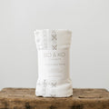 A white muslin baby swaddle wrap with pacific island inspired pattern on it. 