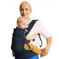 Woman holding a baby in a dark grey Beco baby carrier against a white background