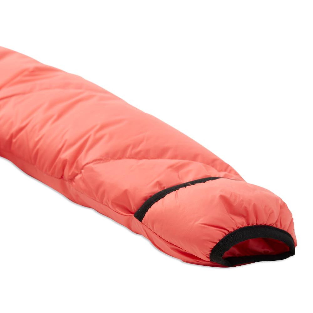 A close-up of a coral pink puffer sleeping bag with black trim, shown on a clean white background.