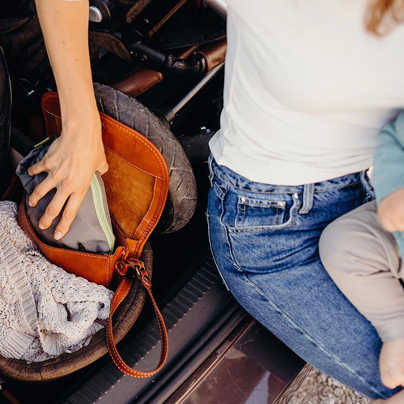 Person organizing items in a car trunk with a saddle and bags.