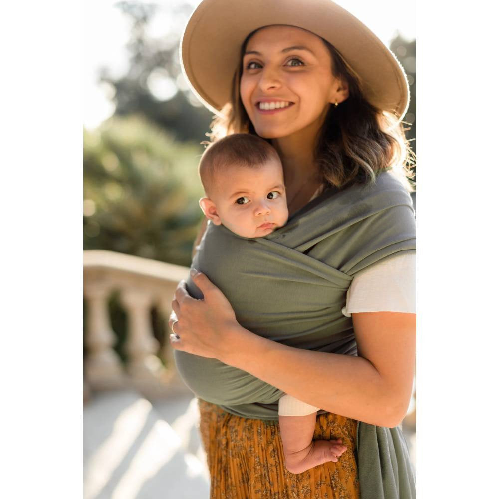Woman holding a baby in a sling outdoors