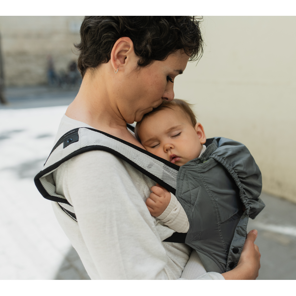 Woman holding a baby in a carrier outdoors