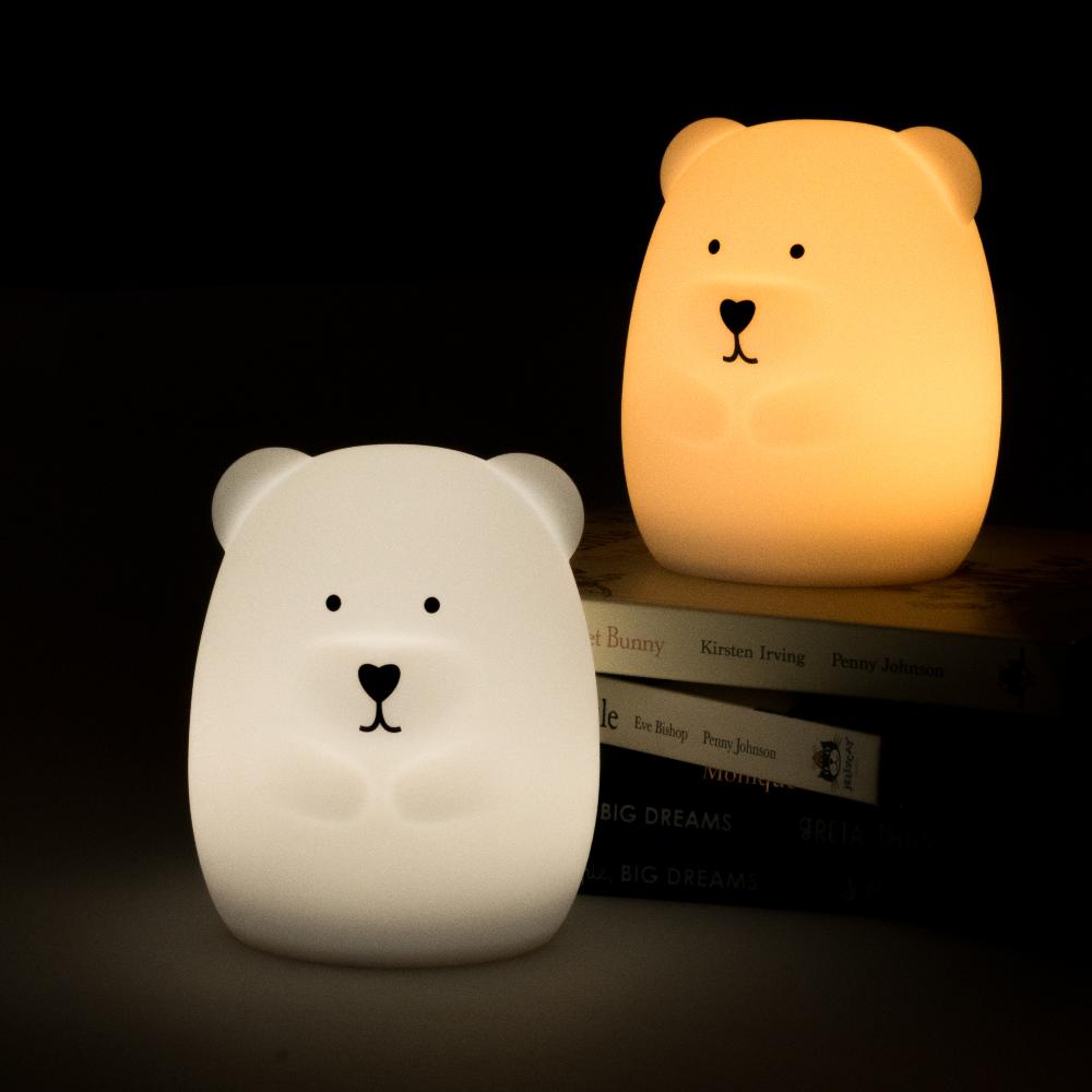 Two bear-shaped silicone night lights, one white and one orange, on a dark background.