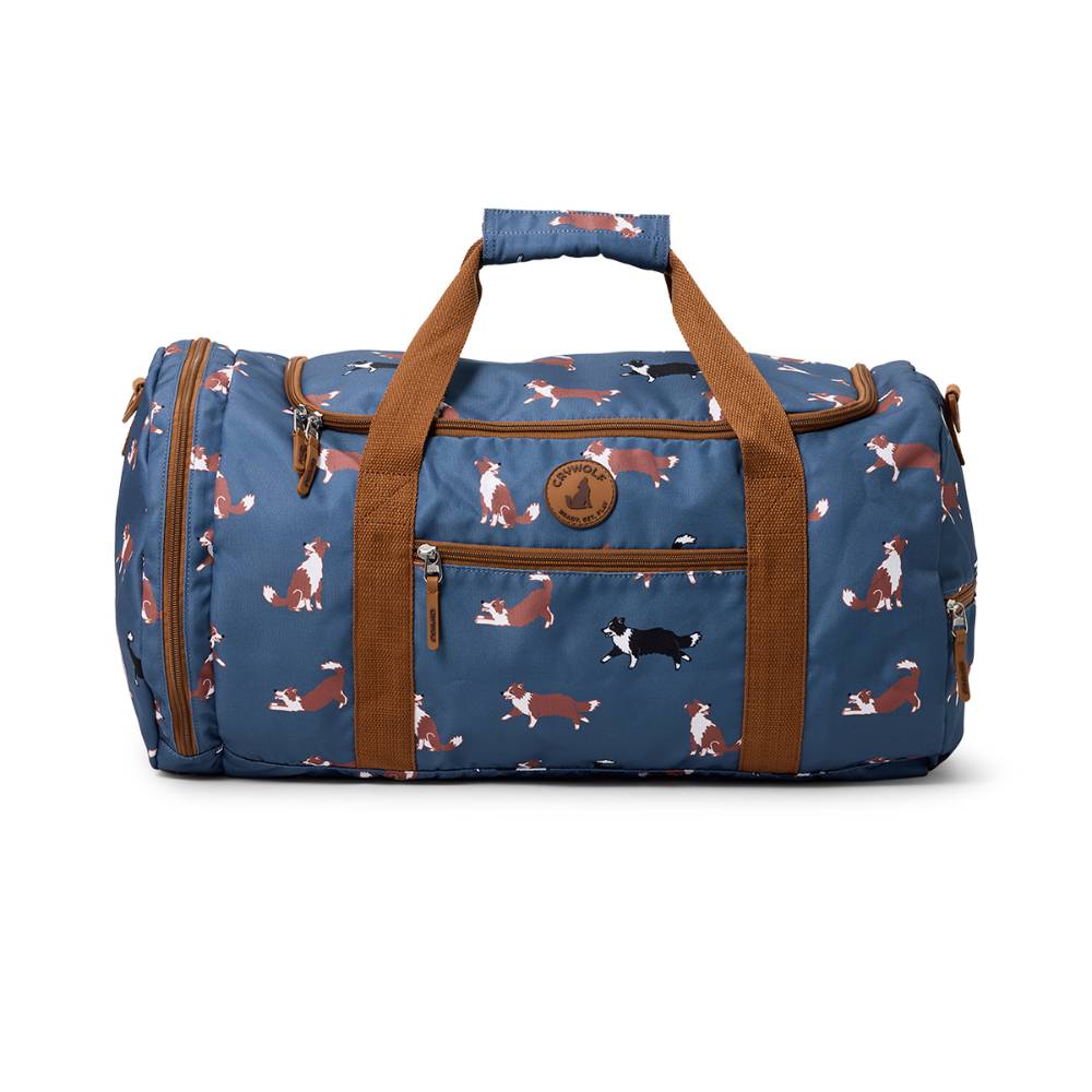 Blue duffel bag with dog pattern and brown handles on a white background