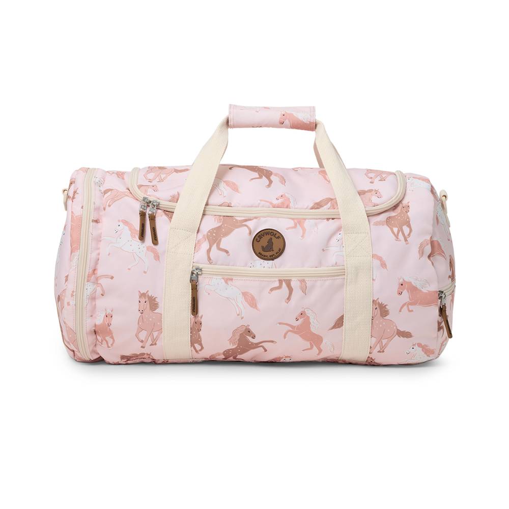 A pink duffel bag with an allover horse print, featuring cream-colored handles and trim, and a circular wooden brand emblem on the front pocket.