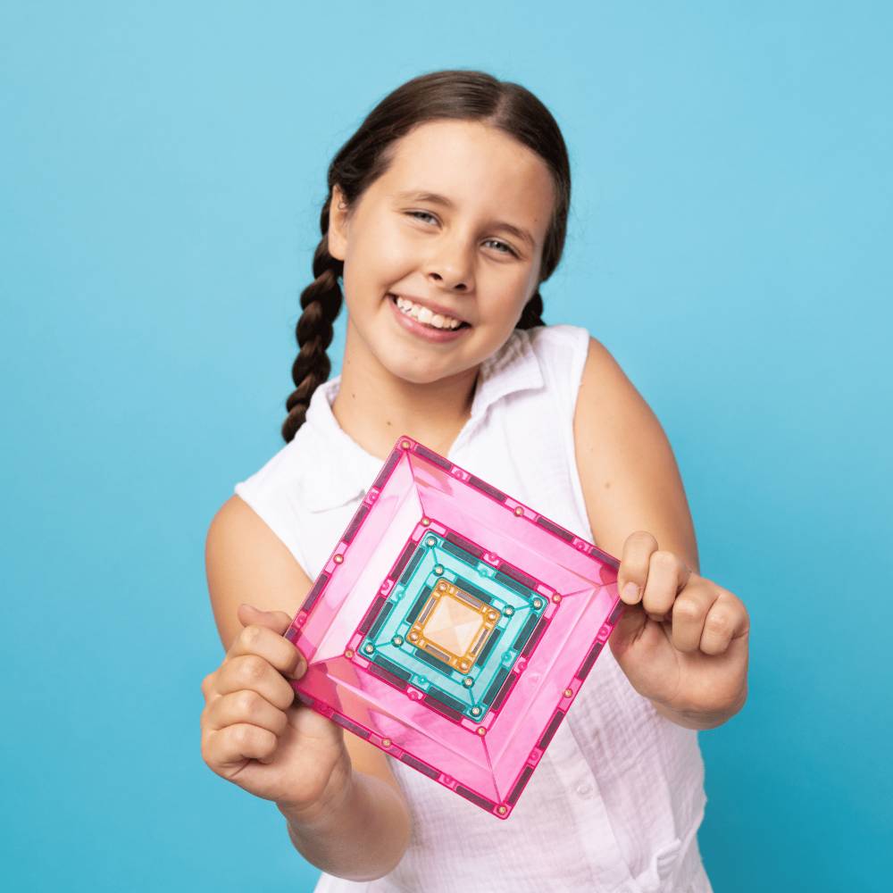 Young girl holding a colorful geometric tile against a blue background