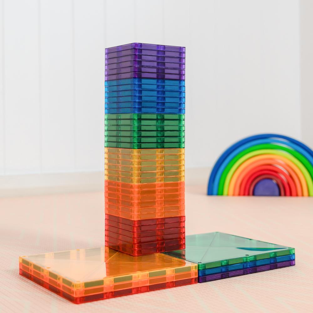 Stack of Connetix colorful transparent building blocks with a rainbow design in the background.