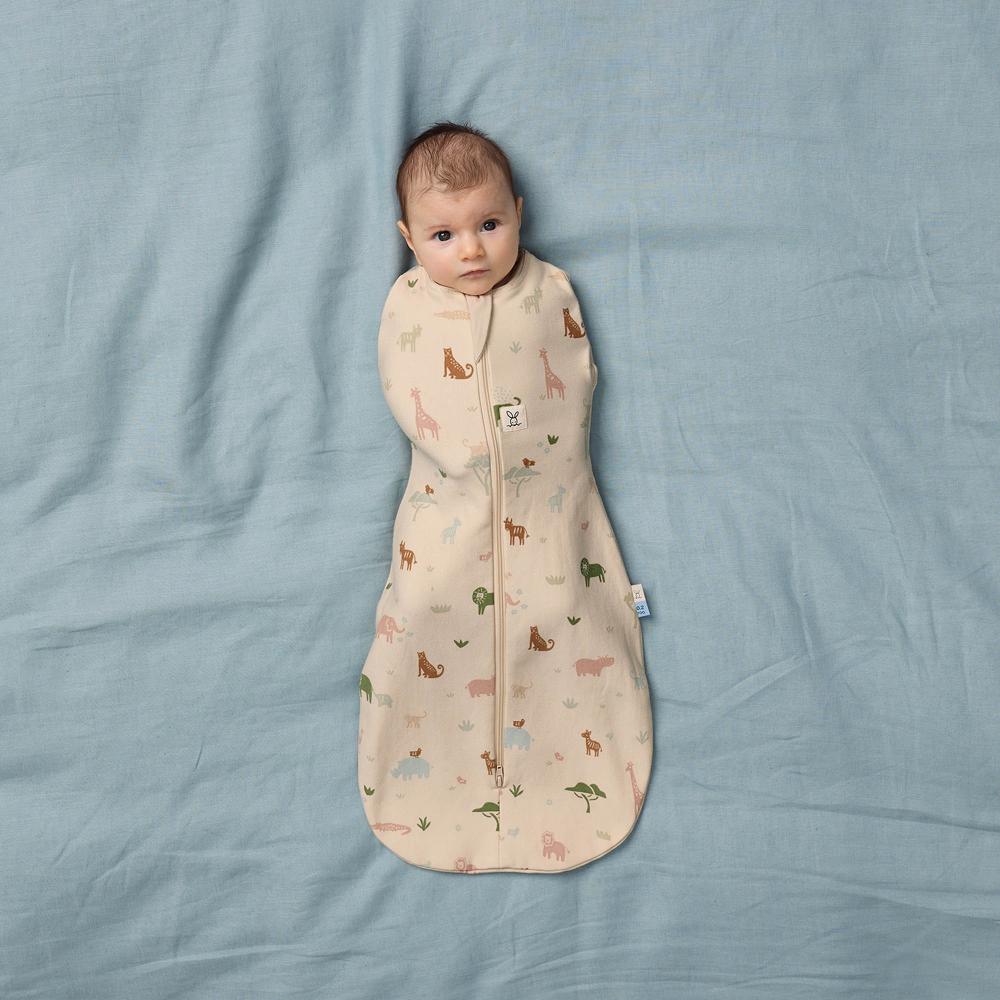 Baby wrapped in a patterned swaddle bag on a blue blanket