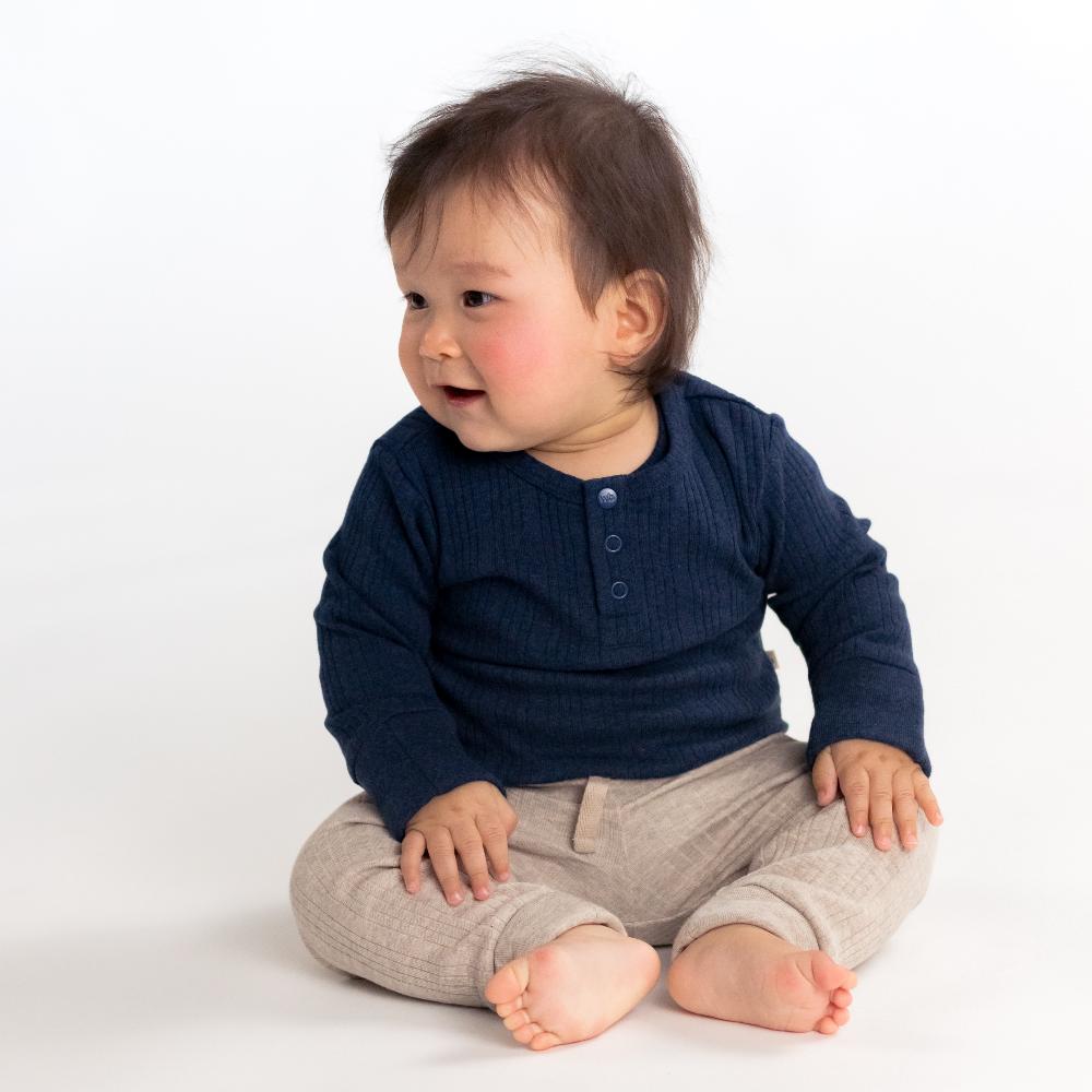 Child wearing a navy blue shirt and Dune Woolbabe Relaxed pants on a white background