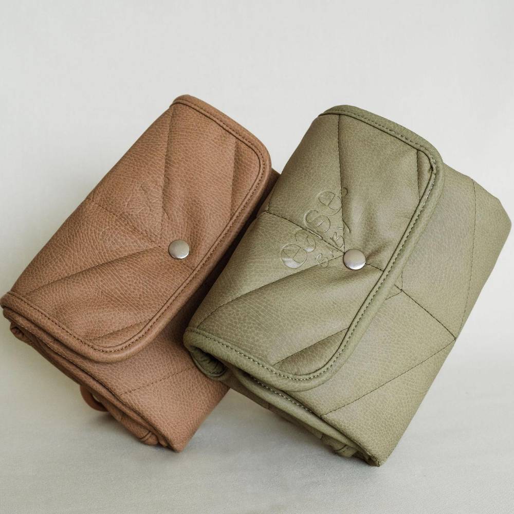 Two quilted leather clutch-style pouches shown on a plain light background, one in tan and one in light olive green, each with a silver snap closure.