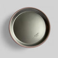 A top-down view of a round stainless steel baby feeding plate with a dusty rose pink rim, featuring the 'ease.baby' logo printed on the bottom right.
