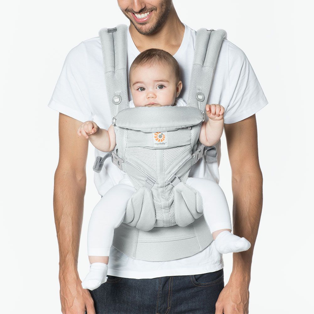 Man holding a baby in a gray baby carrier against a white background
