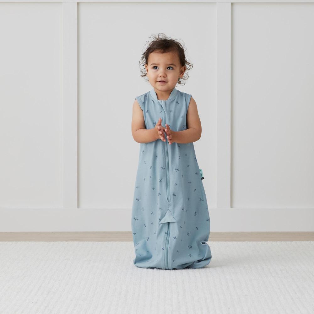 Child wearing a light blue sleeveless sleep sack with a pattern on a white background