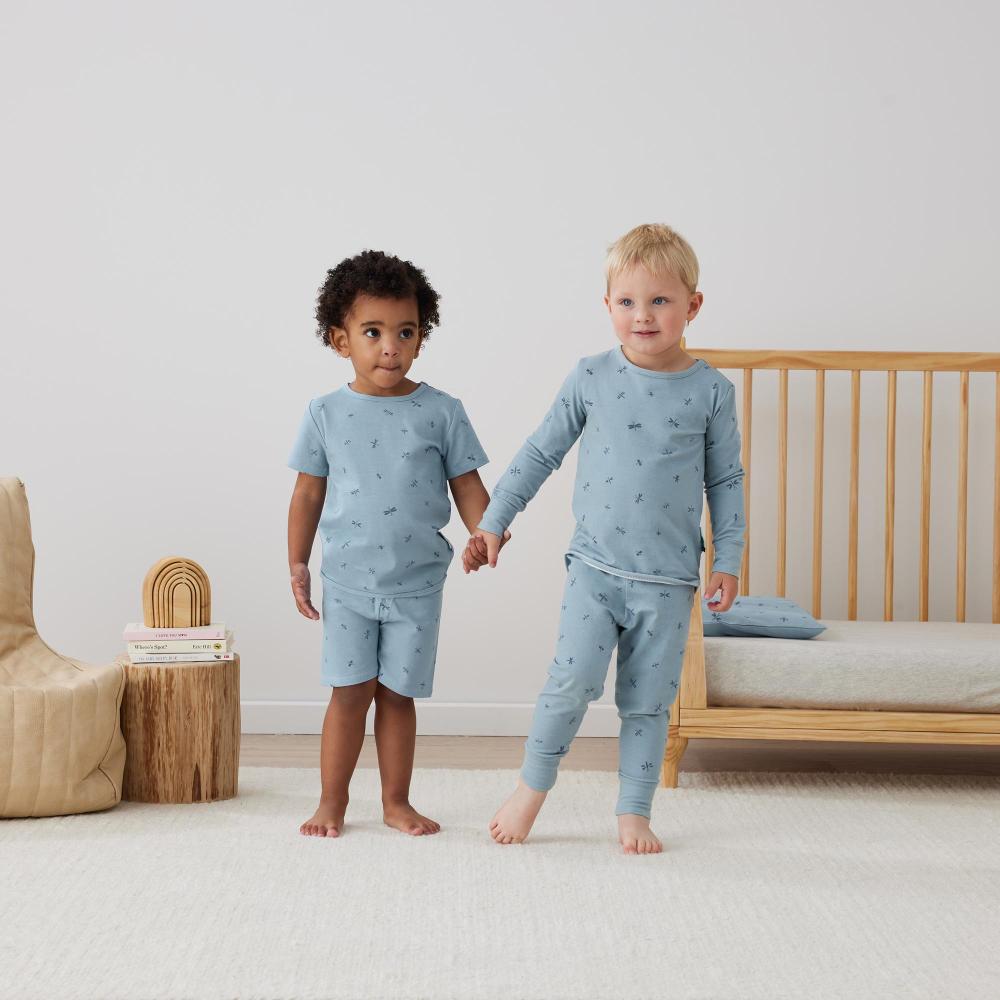 Two children wearing matching blue pajamas in a bedroom setting.