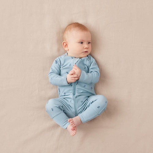 Baby in a blue onesie lying on a beige surface