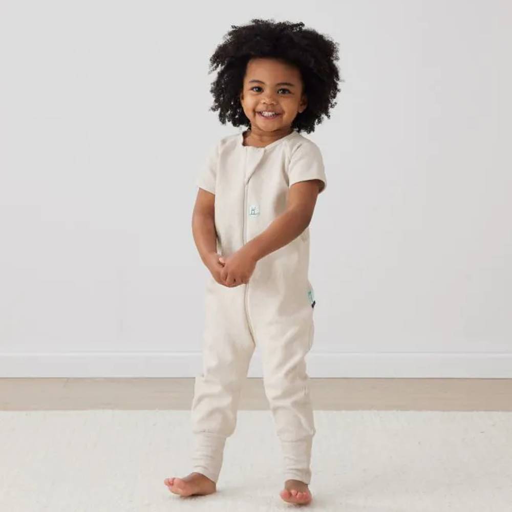 Child wearing a oatmeal coloured onesie on a plain background