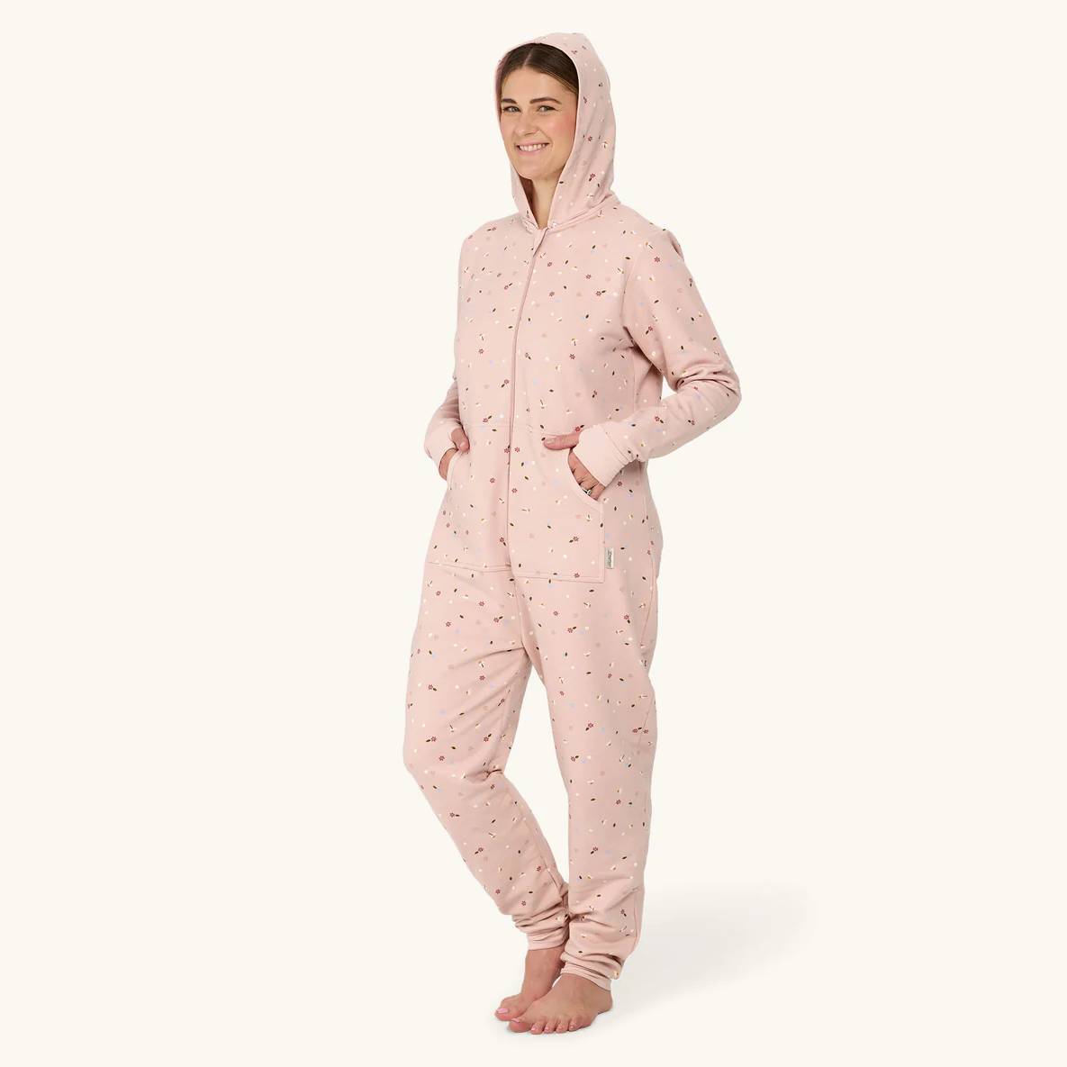 Person wearing a pink onesie with a hood on a white background