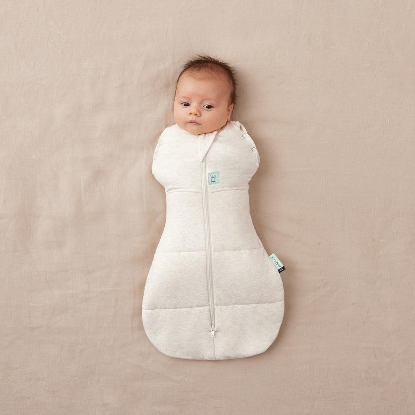Baby wrapped in a oatmeal swaddle on a beige background