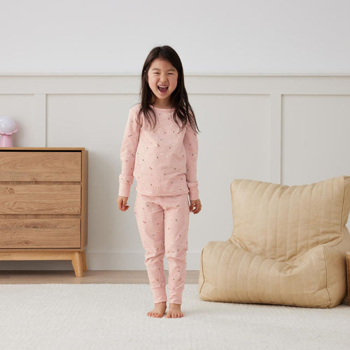 Child wearing pink pajamas in a bedroom setting