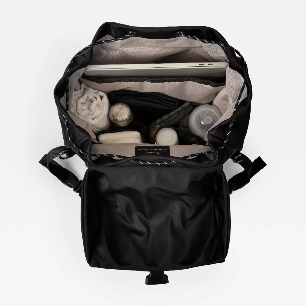 Spacious black nappy bag backpack and change pad with items inside on a white background