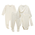 A four-piece baby clothing set in a soft cream/off-white jersey merino fabric, including a long-sleeve footed sleeper, a wrap-style cardigan, and a long-sleeve bodysuit, laid out on a white background.