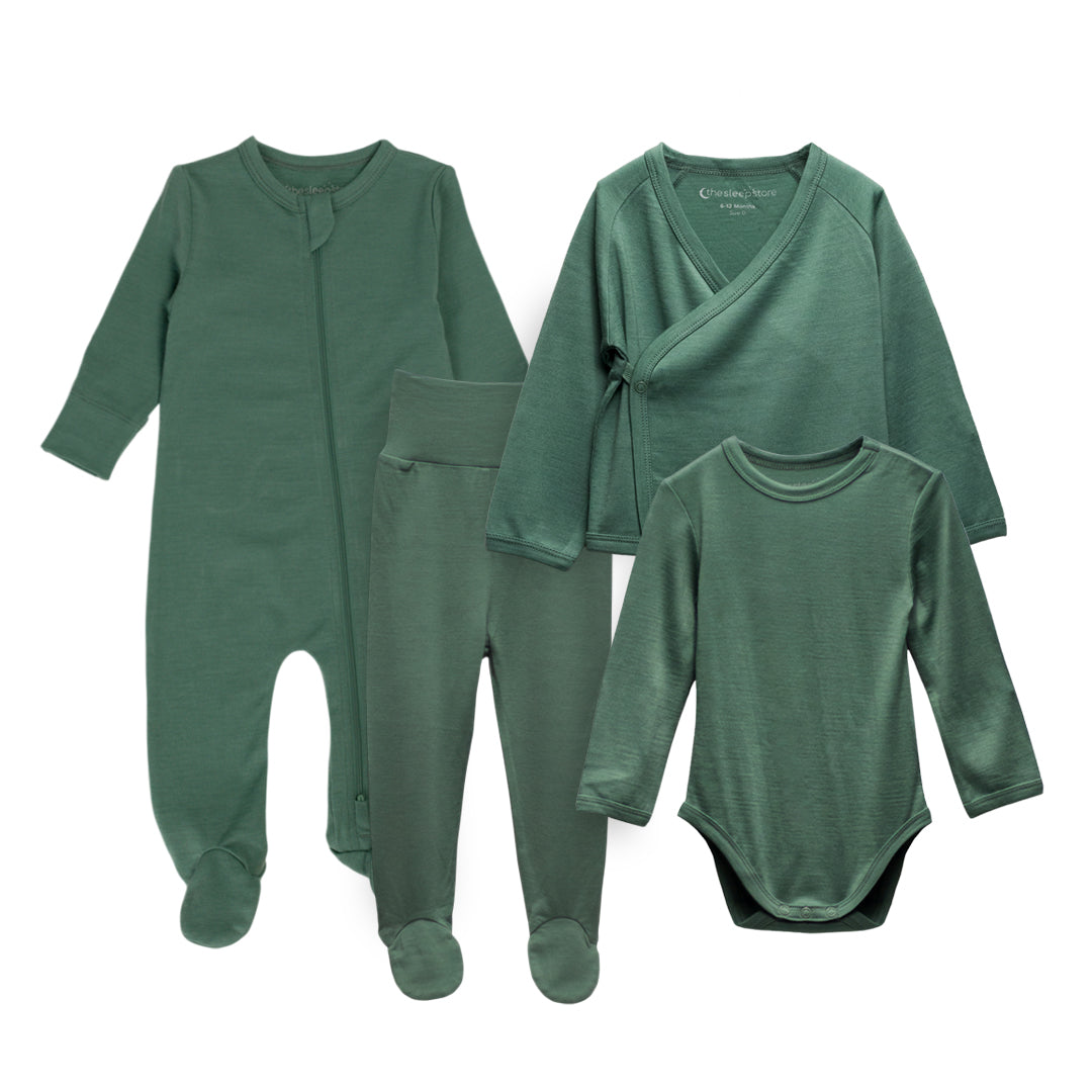 A coordinated baby jersey merino clothing set in a muted sage green color, including a long-sleeve footed sleeper, matching pants, a wrap-style top, and a long-sleeve bodysuit, arranged on a plain white background.
