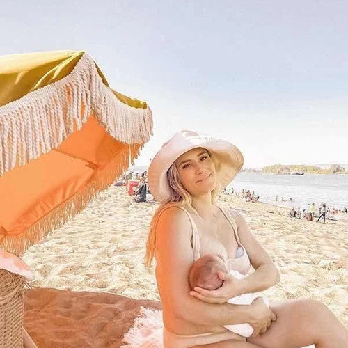 Mother breastfeeding at the beach and using a breastmilk collector 