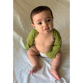 Baby wearing green mitten sleeves against white background.