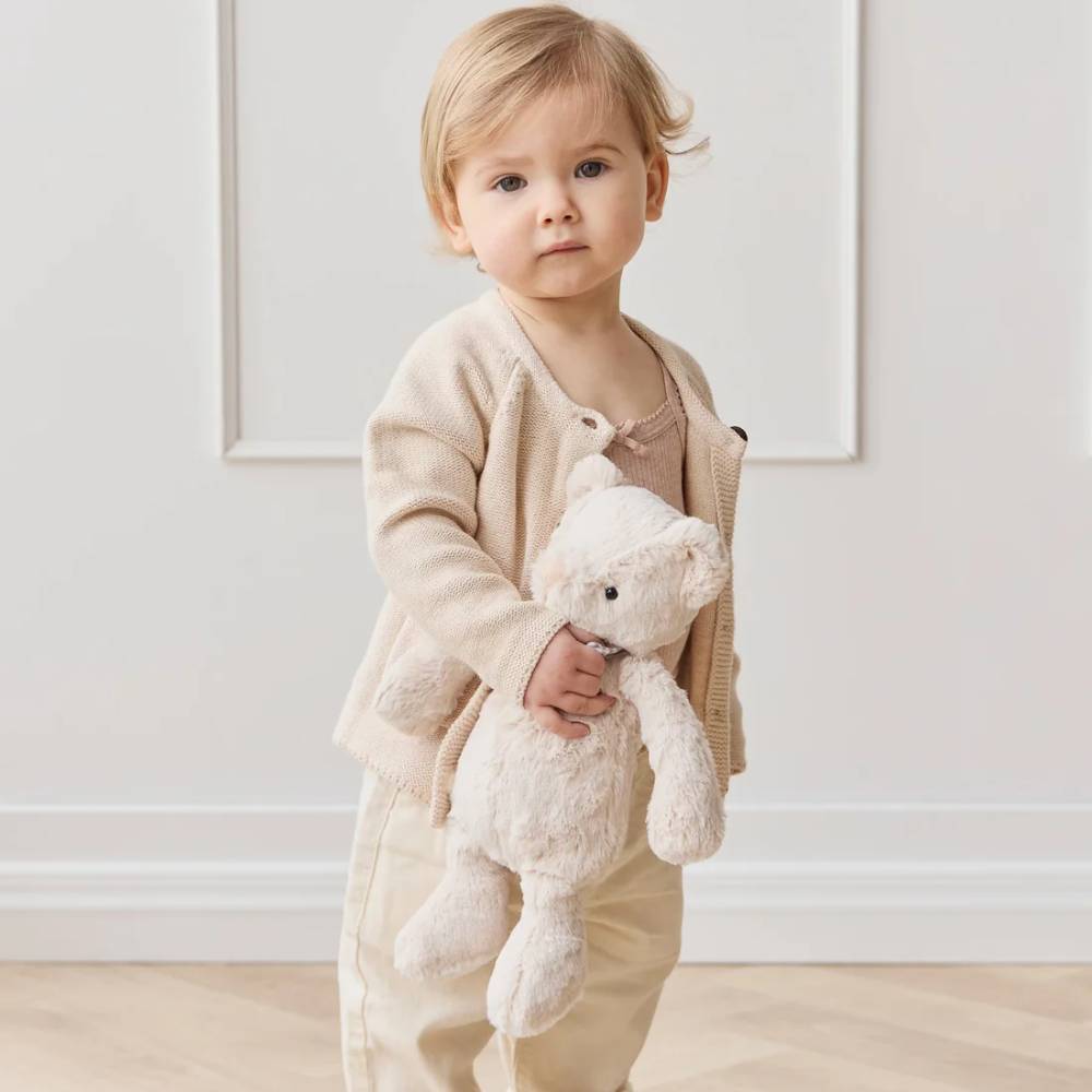 Baby holding Jamie Kay bear soft toy.