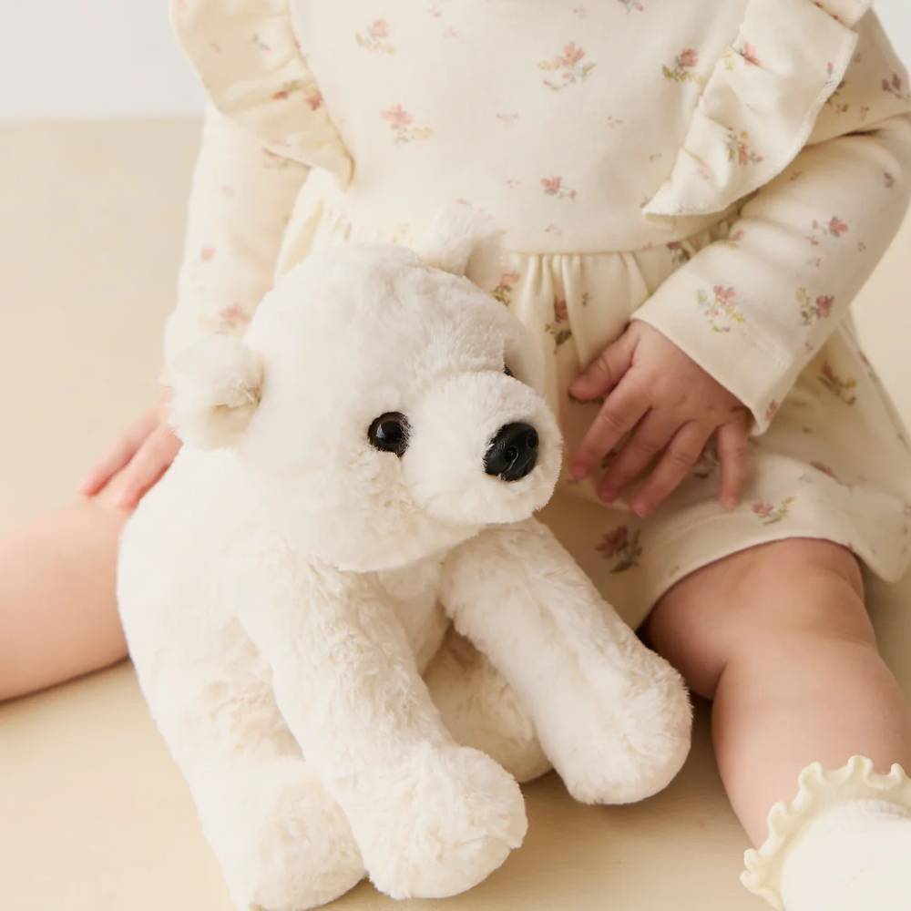 Baby holding white Jamie Kay polar bear soft toy against white background.