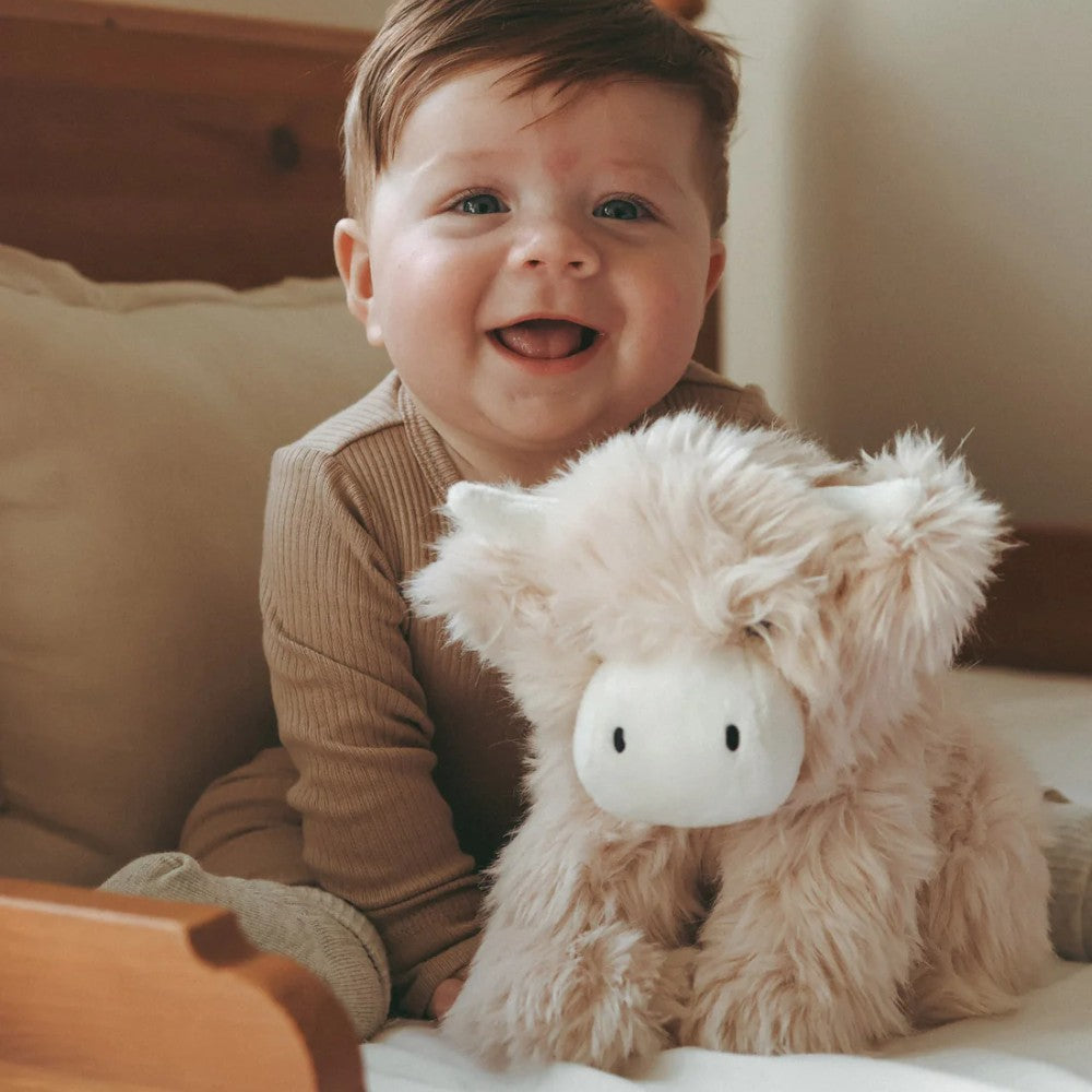 Baby holding Jamie Kay cow soft toy.