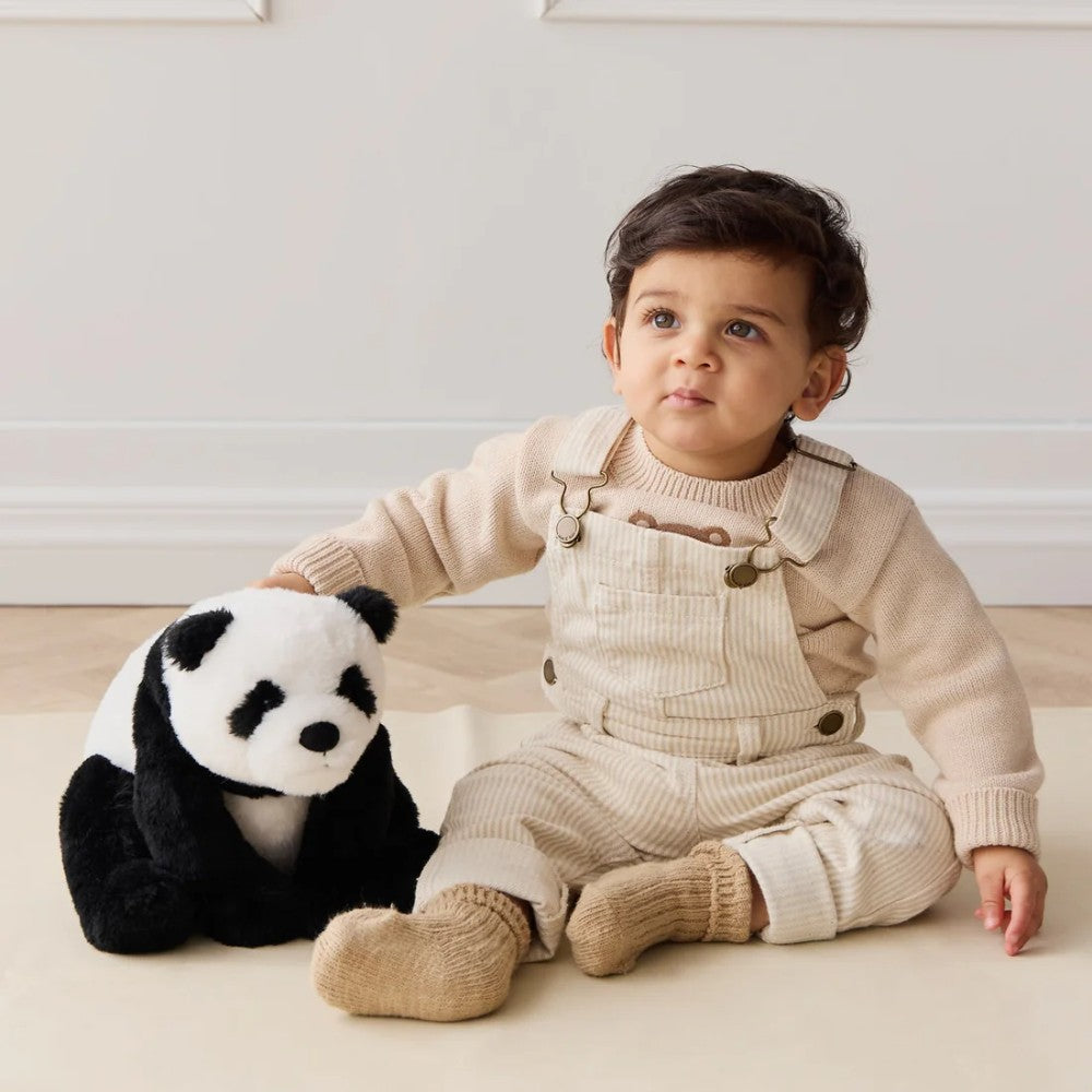Baby sitting on floor with Jamie Kay black and white panda soft toy.