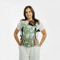 A woman wearing a green baby carrier with white birds on it and a baby inside. 