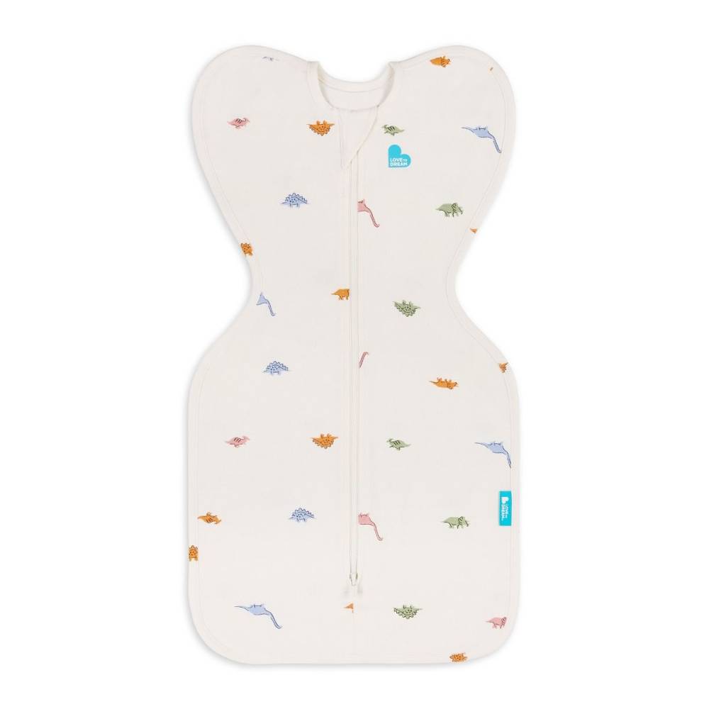 An off-white baby sleep swaddle with a front zipper, decorated with a small pattern of colorful dinosaurs and a small blue heart logo on the chest.