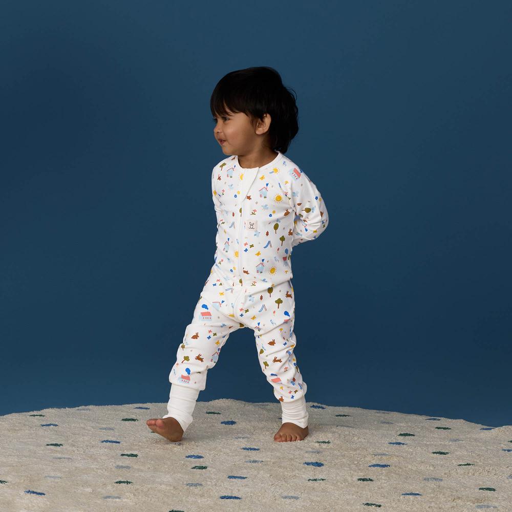 Child wearing a white pajama set with colorful patterns on a blue background