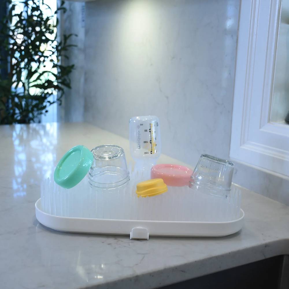Set of baby bottles and accessories on a white tray with a blurred background