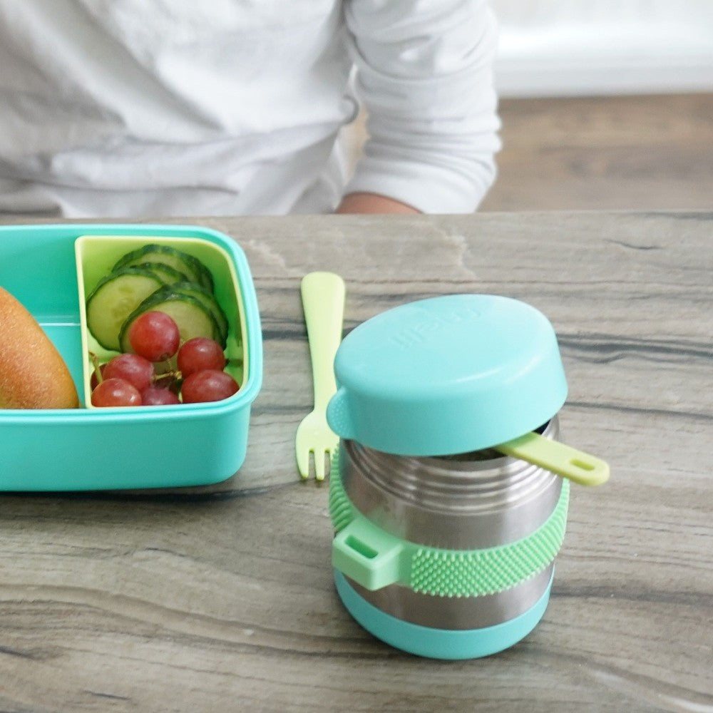 Children's lunchbox with a snack container and a small green and blue insulated bottle on a wooden surface.