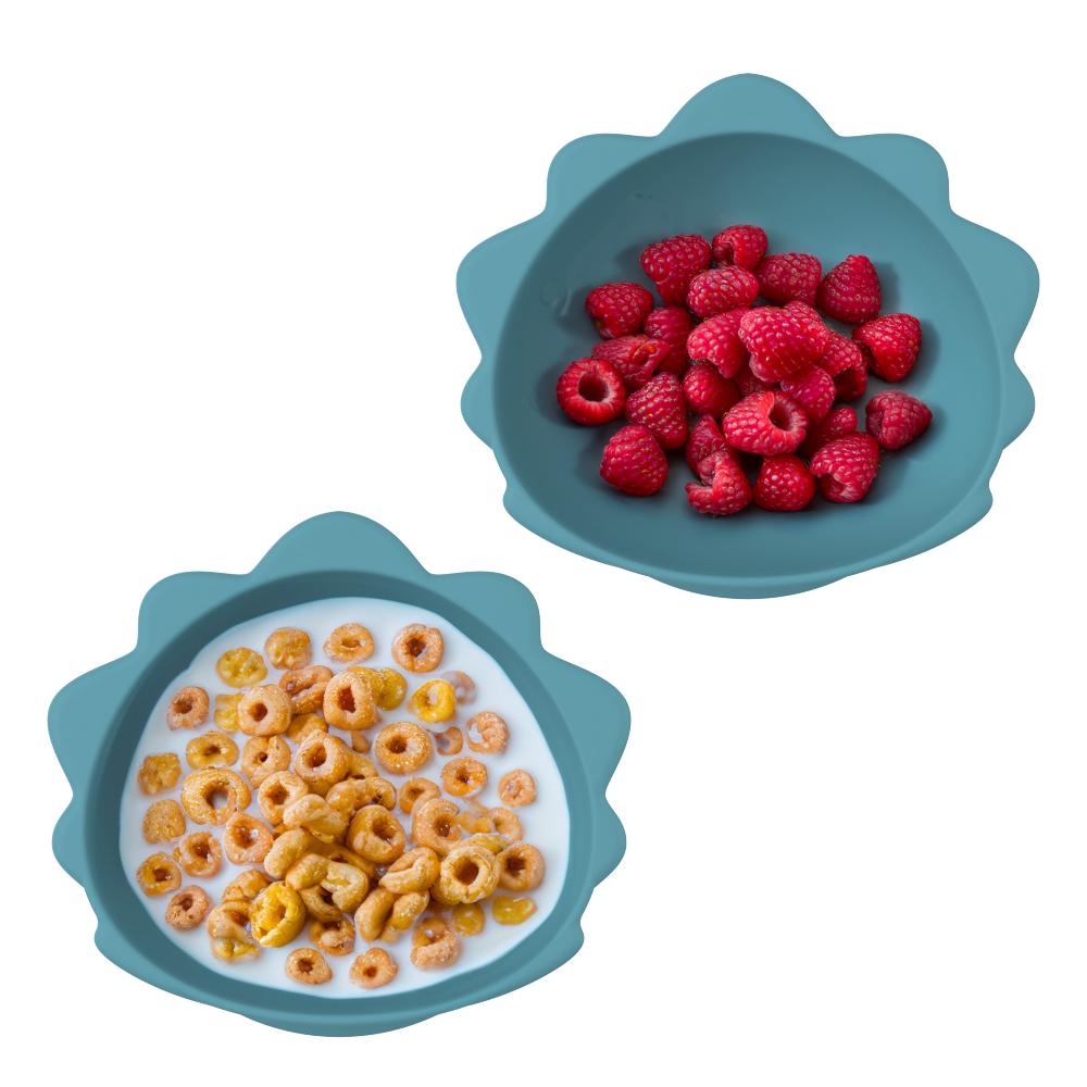 Two blue bowls with cereal and raspberries on a white background
