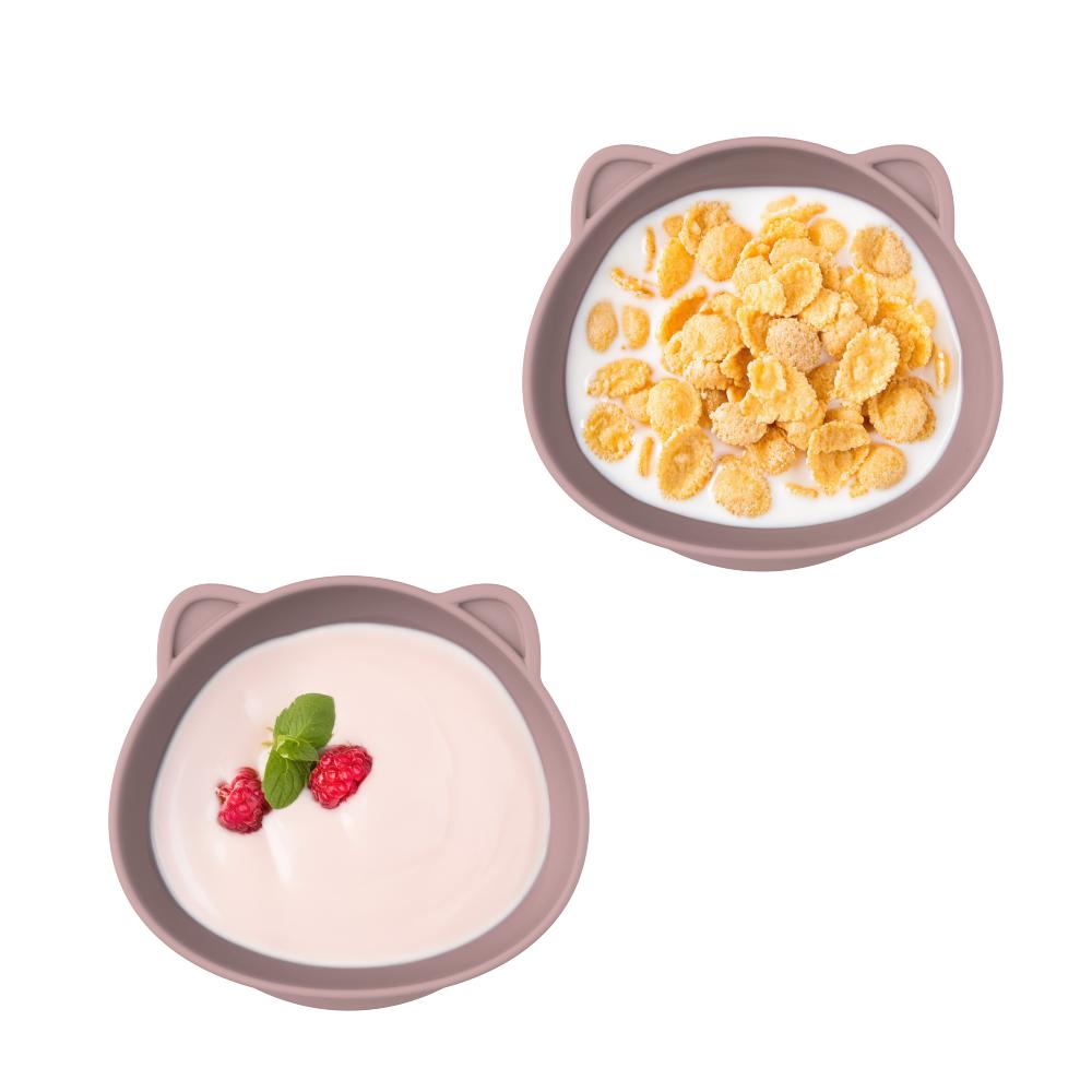 Two cat-shaped bowls with one containing cereal and the other with yogurt and berries on a white background.