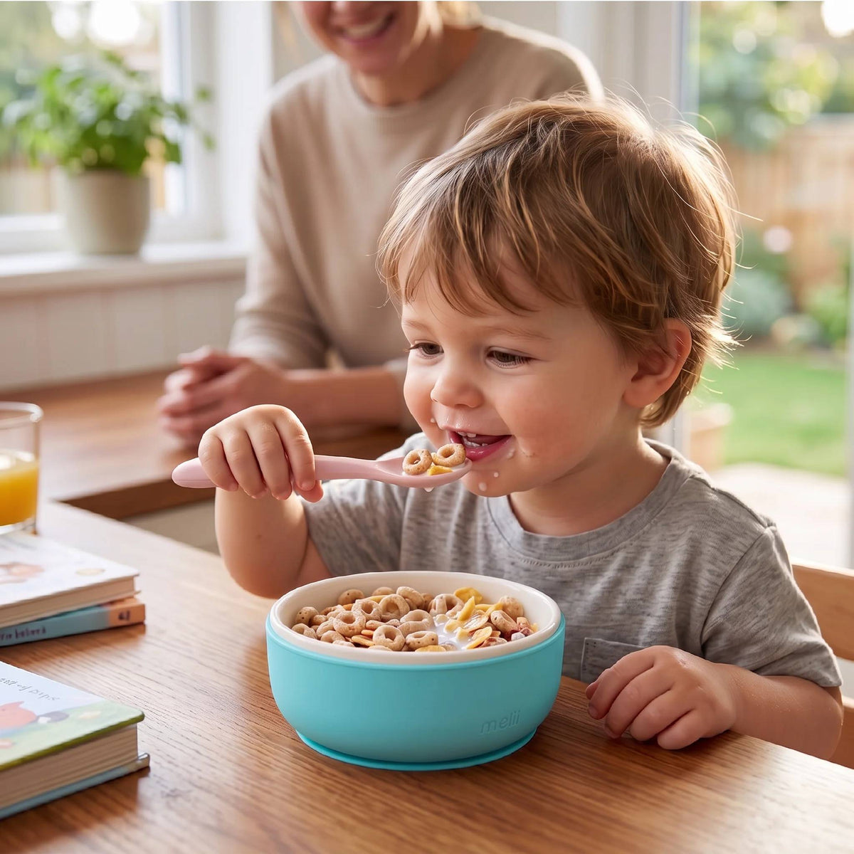 A young boy eating cereal from a ceramic bowl with blue silicone sleeve. 