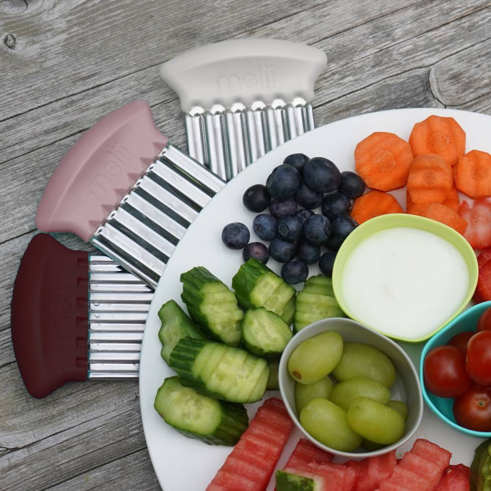 Fruit and vegetable platter with a kitchen tool on a wooden surface