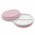 A ceramic divided plate with a pink silicone sleeve, on a white background. One plate is overturned to show the suction base. 
