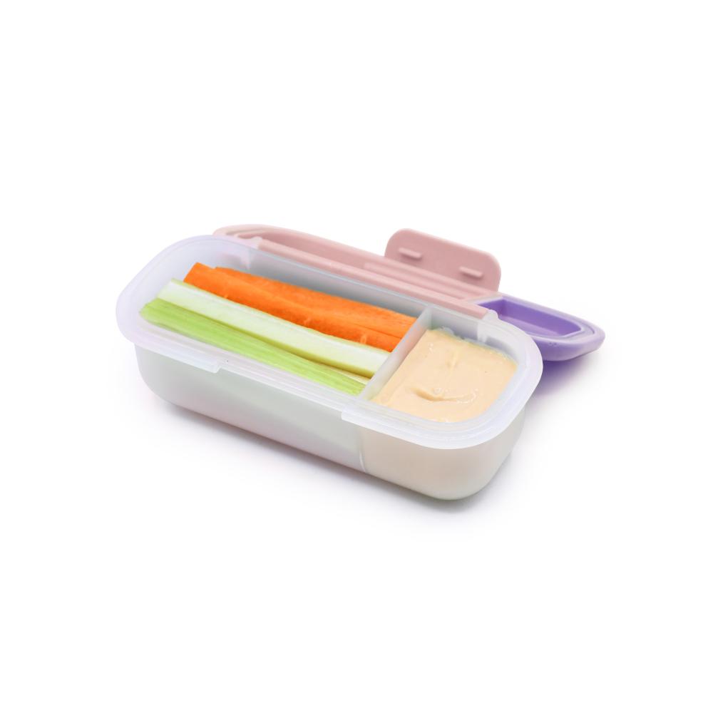 Container with compartments filled with vegetable sticks and dip on a white background