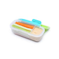 Container with compartments filled with vegetable sticks and dip on a white background