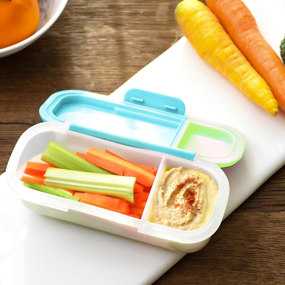 Bento box with hummus and vegetable sticks on a wooden table