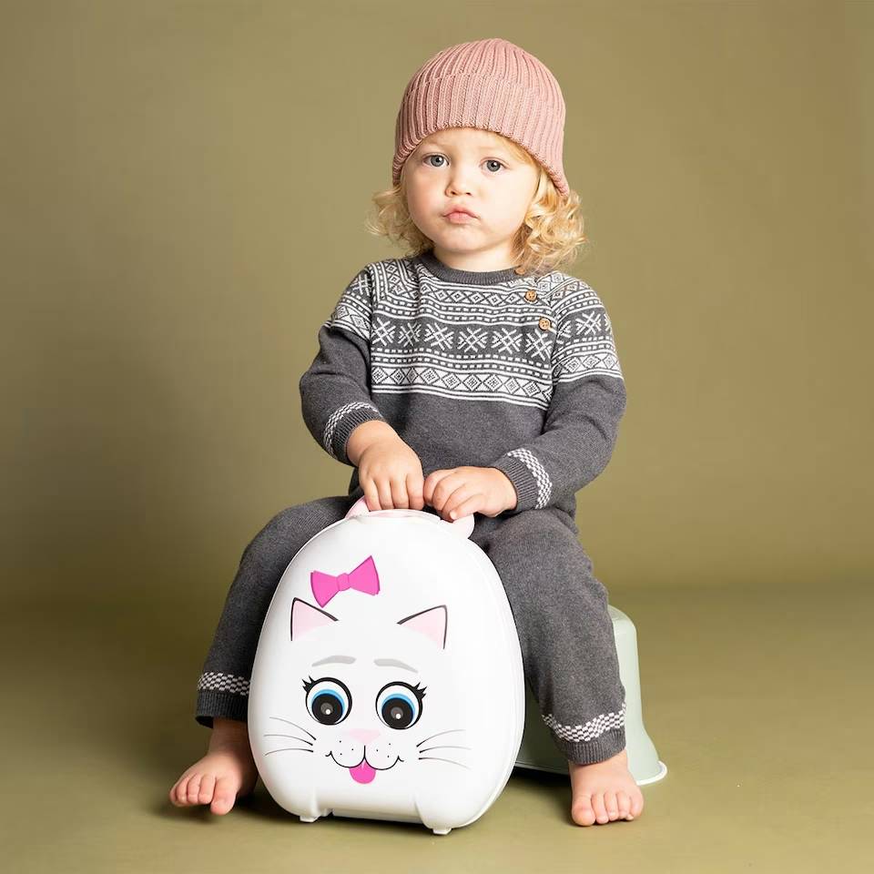 Baby holding My Carry Potty against green background.