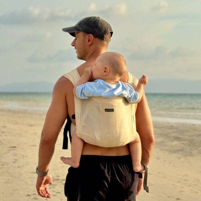 A man holding his baby on his back in a Mini Monkey Toddler carrier in the colour Sand 