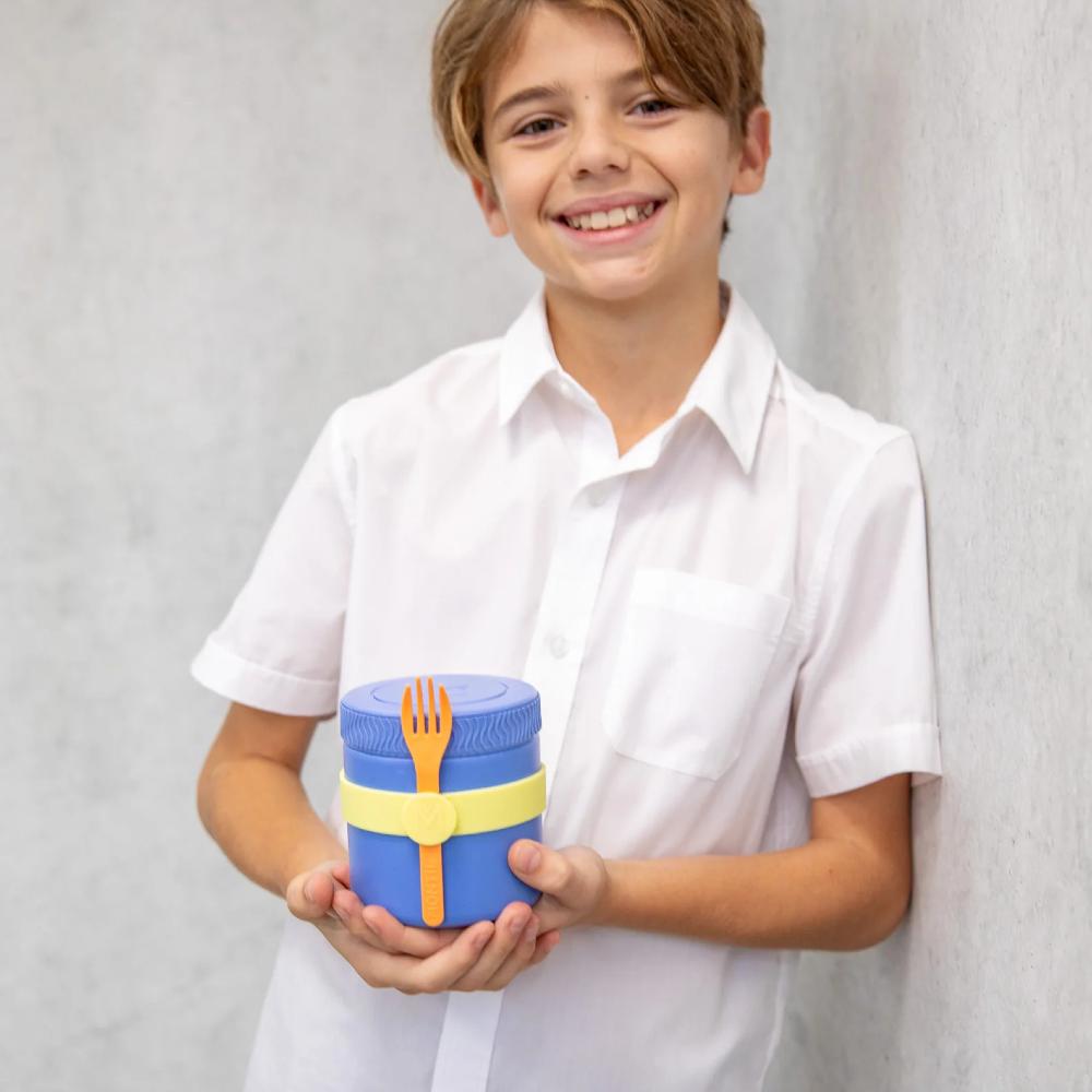Child holding a blue container with a yellow fork against a plain background